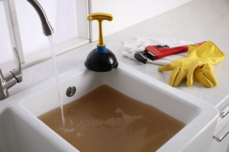 clogged-kitchen-sink-with-plumbger-on-counter